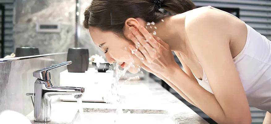 Woman washing face at night with water splashing
