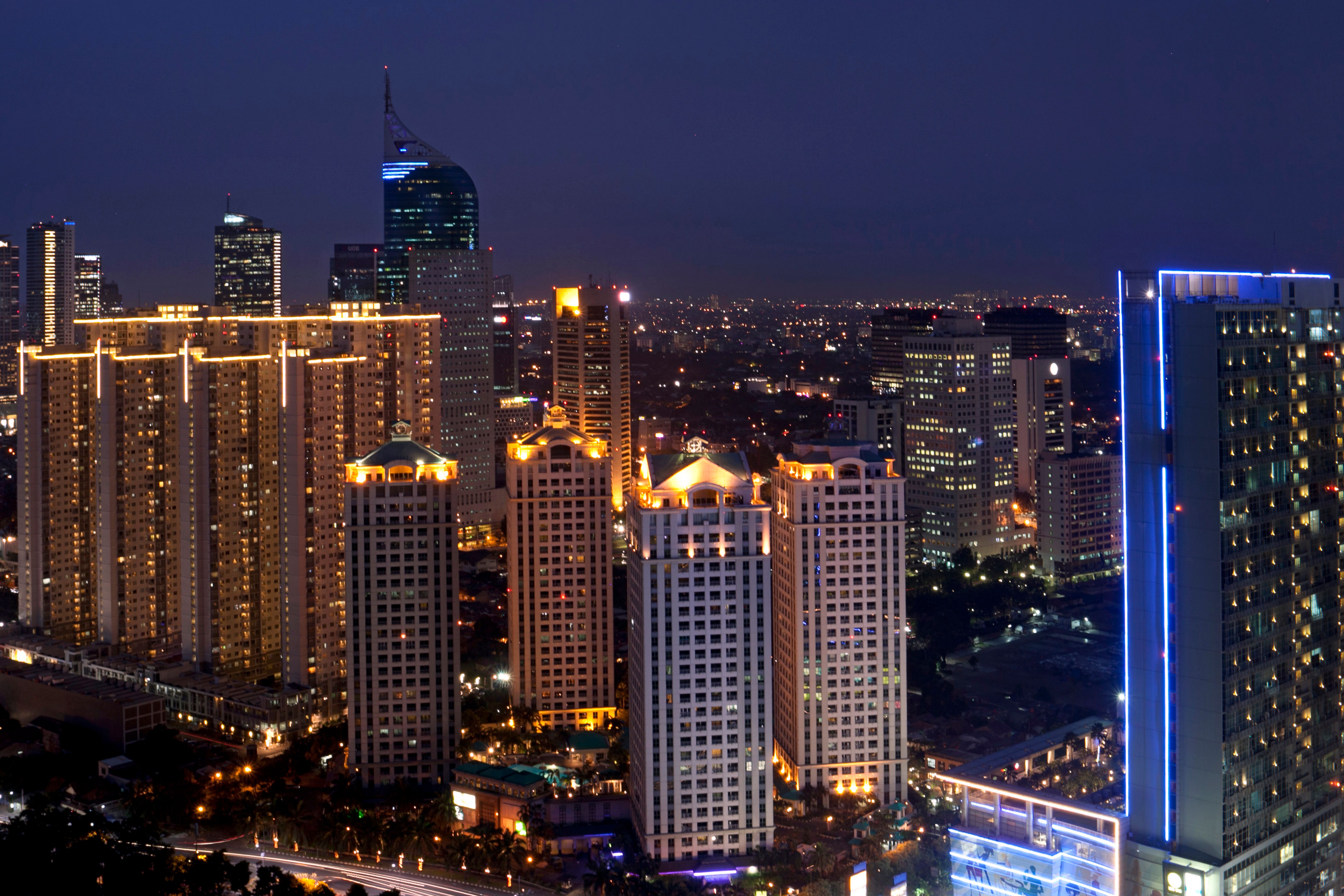 Jakarta city skyline at dusk with illuminated office buildings and advertising billboards reflecting Indonesia's vibrant advertising and media industry