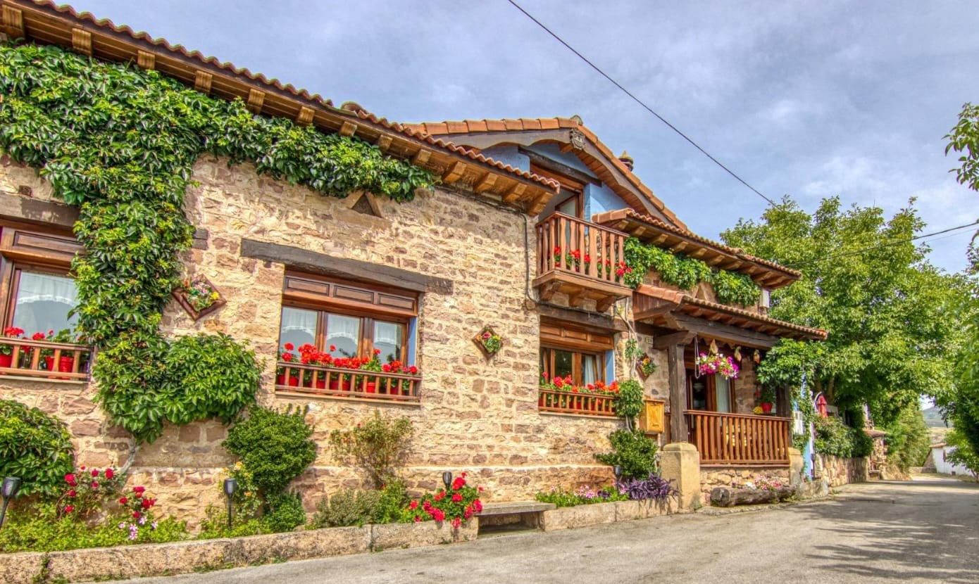 Casa de piedra con hiedra y flores rojas