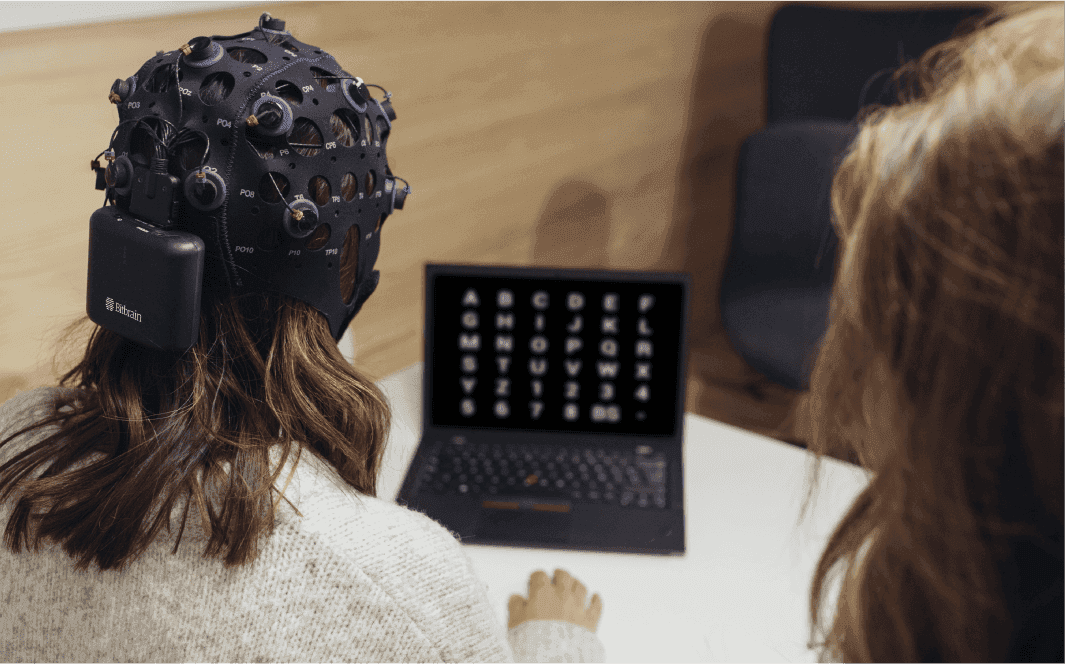 Persona utilizando un casco de electroencefalografía frente a una computadora