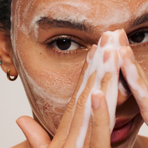 Close-up of woman washing face with foam cleanser