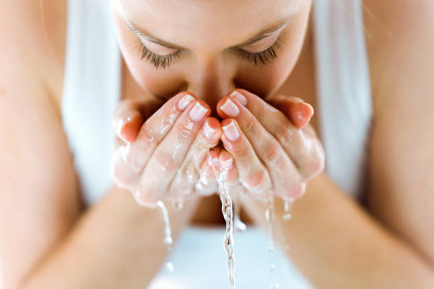 Woman washing face with cupped hands in morning