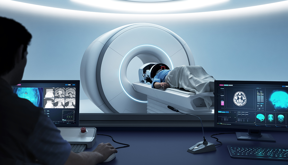 Médico operando un ordenador mientras un paciente está en una máquina de resonancia magnética