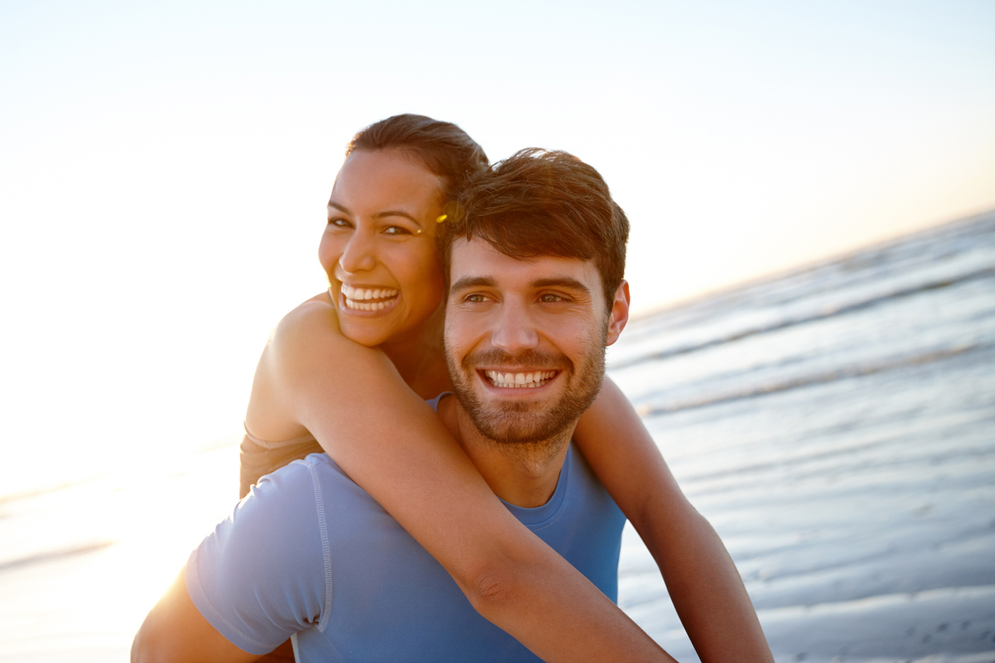 Pareja sonriente en la playa, mostrando similitudes físicas