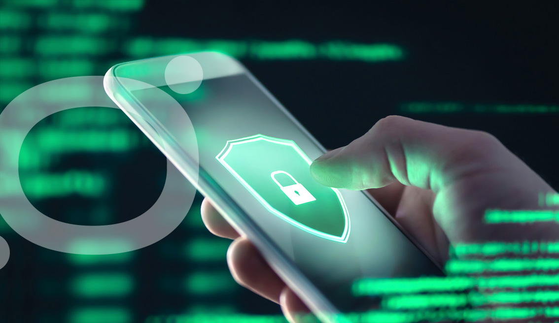 Mano sosteniendo un smartphone con un escudo de seguridad en la pantalla