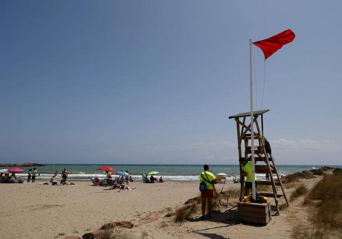 Socorrista vigilando playa con bandera roja