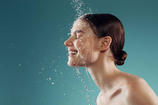 Woman washing face with water splashing