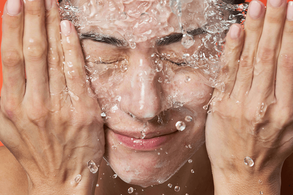 Woman's face being splashed with water, eyes closed in enjoyment