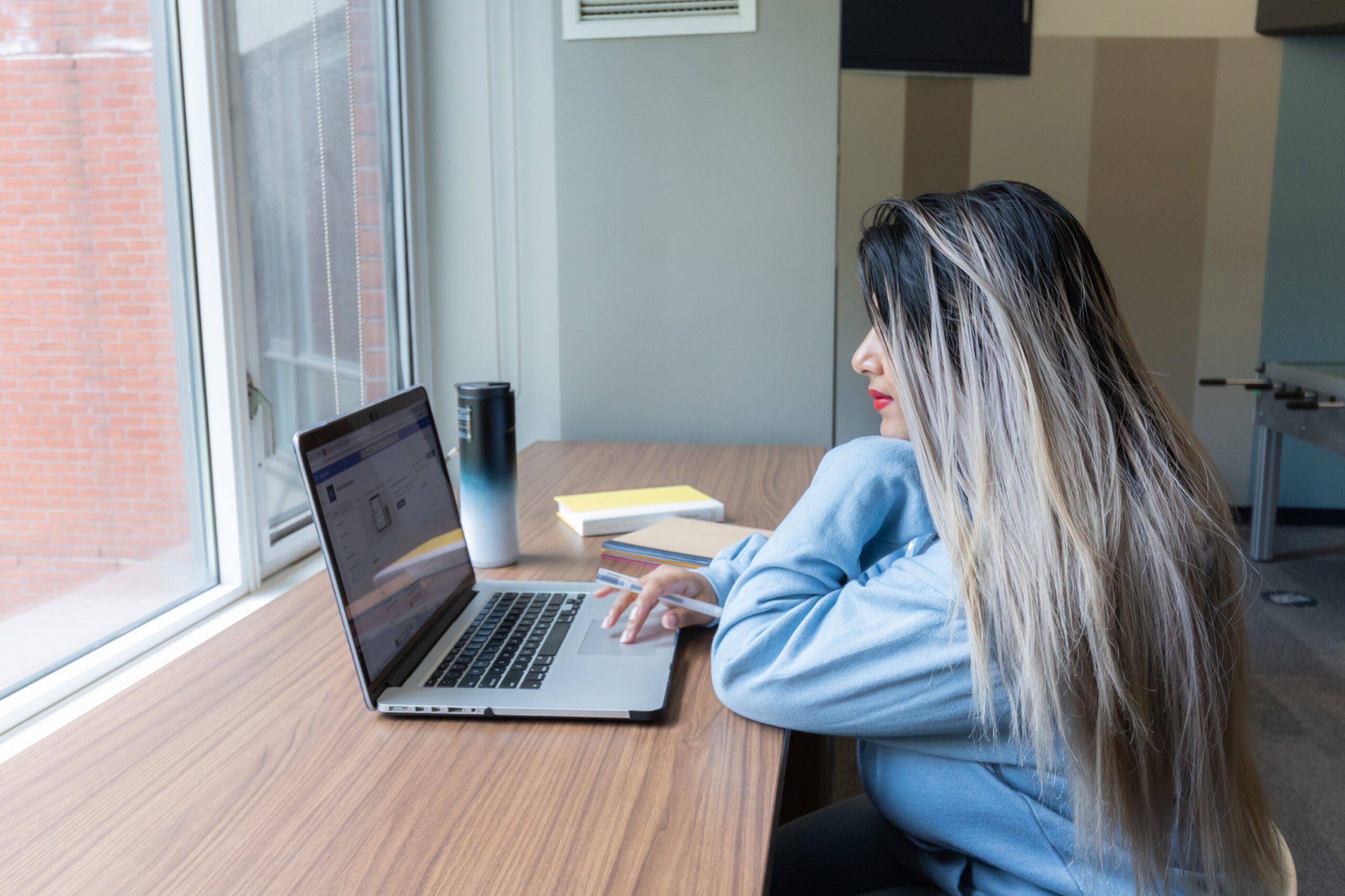 Social work student studying with laptop and textbooks