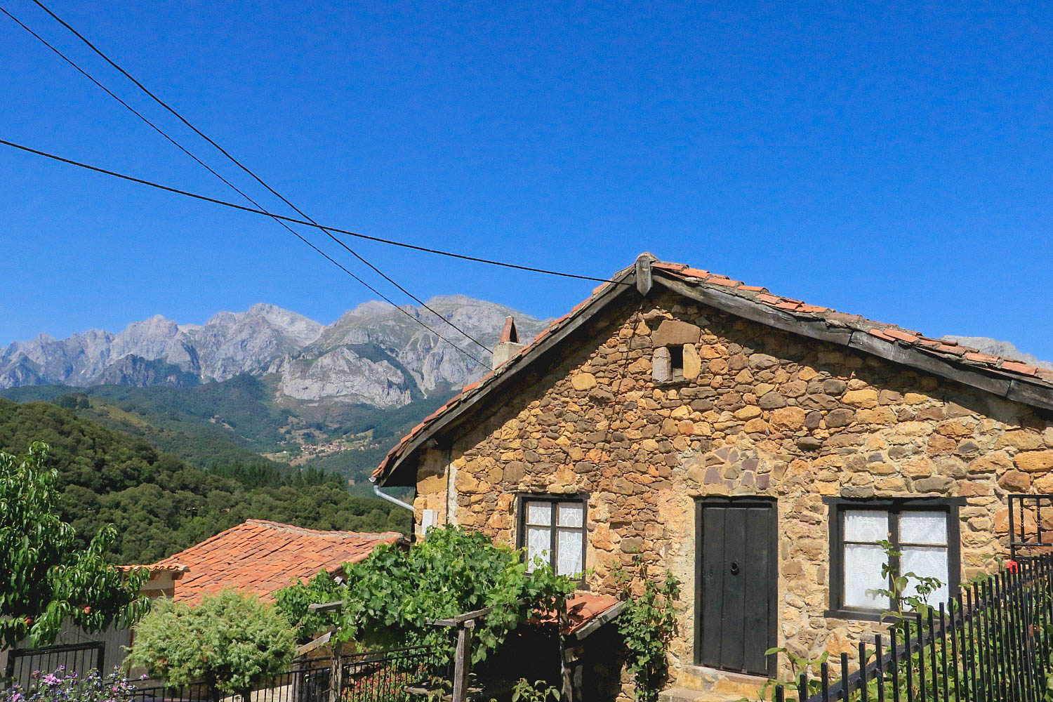 Casa rural de piedra con tejado rojo al pie de las montañas