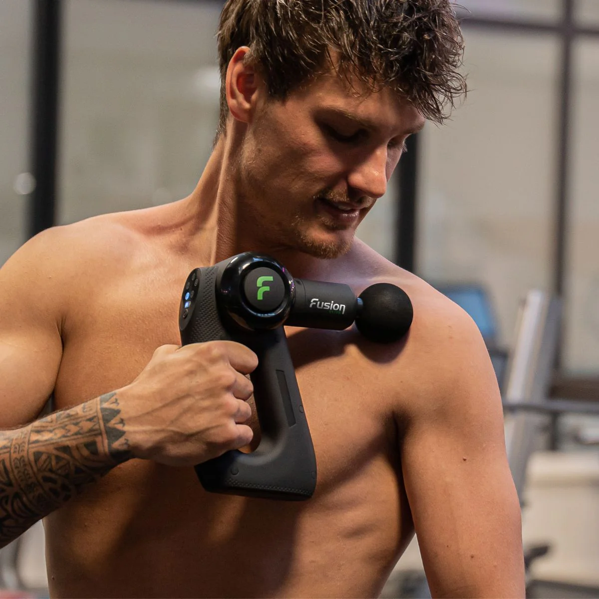 Man using massage gun on shoulder for muscle knot relief